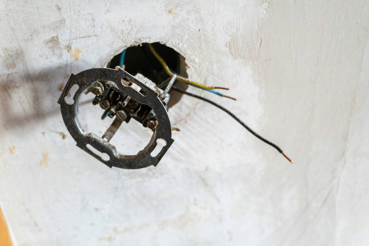 how to open recessed light fixture showing hands gently releasing spring clips on a white ceiling-mounted housing